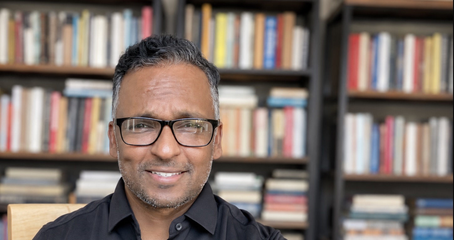 Riley Konara, MD — psychiatrist and reader, in front of his bookshelves